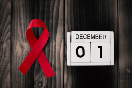 Red ribbon with calendar date 1 December on brown wood background, Concept World Aids Day.の写真素材