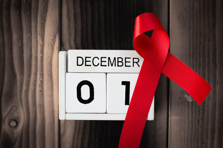 Red ribbon with calendar date 1 December on brown wood background, Concept World Aids Day.の写真素材