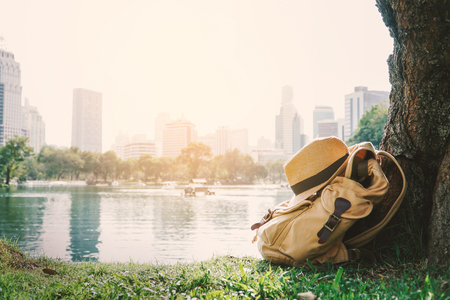 Yellow bag for backpack under the tree with city background ,concept travel around the world.の写真素材