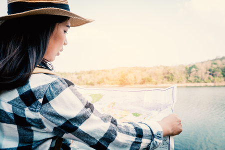 Asian woman looking for destination in a map, backpack on the park journey and traveling on holiday concept.の写真素材