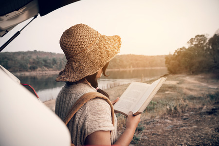 Asian woman sitting in eco car and reading a book enjoying with the hobby time .の写真素材