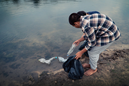 The volunteer picking up a bottle plastic in the river , protect environment from a water pollution concept.の写真素材