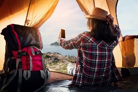 Hipster woman resting and selfie in the tent picnic on holiday with the beautiful sea view...