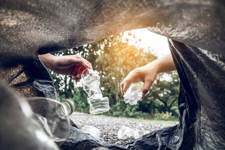The volunteer picking up a bottle plastic in the park, protect environment and pollution concept.
