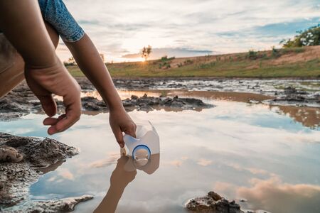 Boy scooping water from the lake, drought and global warming.