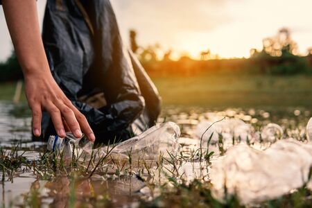 Human picking up a bottle plastic in the river, protect environment from a water pollution concept.