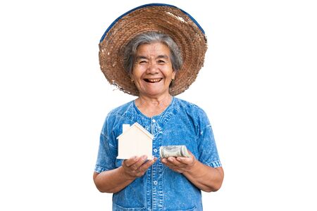 Happy old farmer woman holding little wood house on a white background.の写真素材