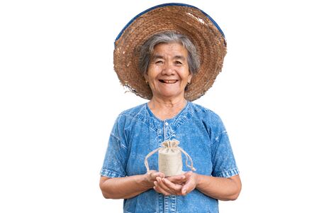 Happy old farmer woman holding a money bag on a white background.の写真素材