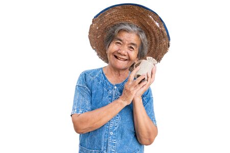 Happy old farmer woman holding a money bag on a white background.の写真素材
