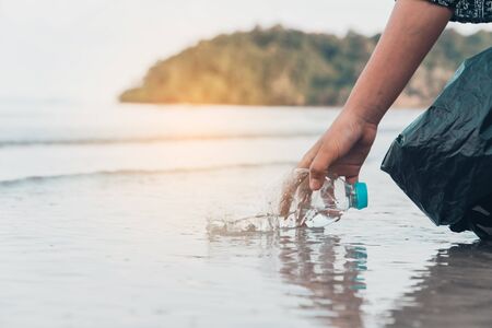 Hand picking up plastic bottle cleaning on the beach , volunteer concept.の写真素材
