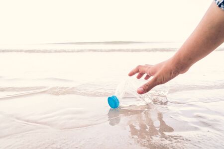 Hand picking up plastic bottle cleaning on the beach , volunteer concept.の写真素材
