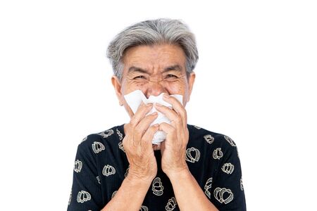 An old woman have a cold, uses a tissue to cover her mouth when coughing and sneezing, covid 19の写真素材