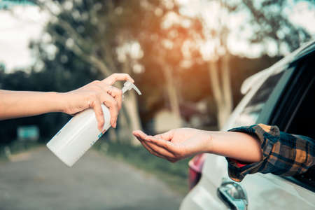 Woman cleaning a hand with 75% alcohol gel before driving through the screening to prevent Coronavirus or Covid-19の写真素材