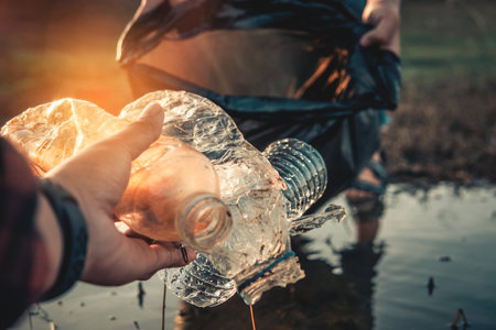 Human hand keeping plastic bottle and garbage in the natureの写真素材