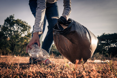 Human hand keeping plastic bottle and garbage in the natureの写真素材