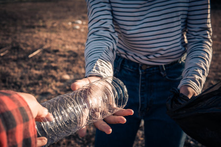 Human hand keeping plastic bottle and garbage in the natureの写真素材