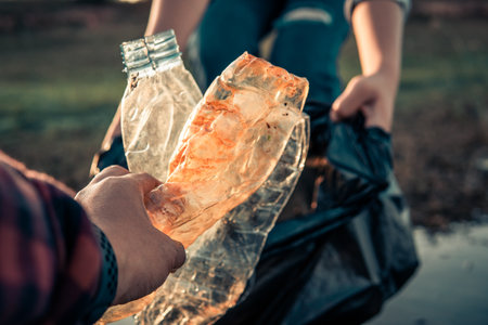 Human hand keeping plastic bottle and garbage in the nature