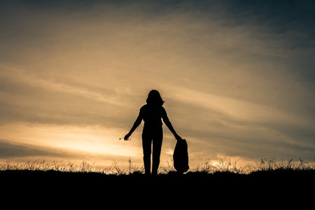 Silhouette woman holding plastic bag volunteer to keeping the garbage in the natureの写真素材