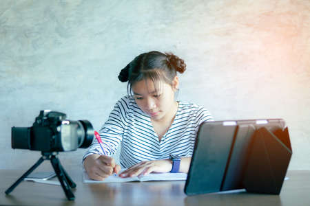 Asian student using smart tablet study online at home.
