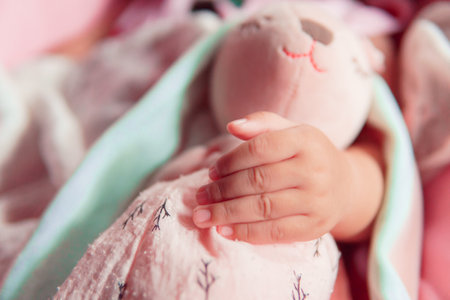 the baby sleeping and hugging her doll.
