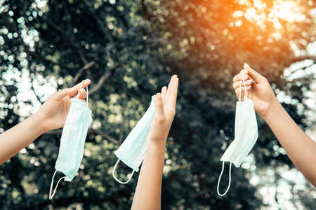 People holding a mask take off their masks to loosen the lockdown. Life safety after vaccinationの写真素材