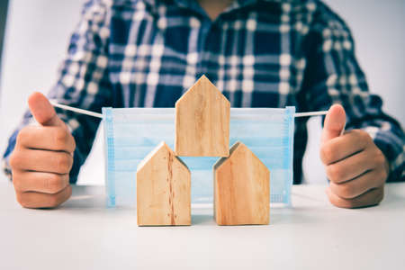 Human hand protects wood house model, the residential crisis in the  situation.の写真素材