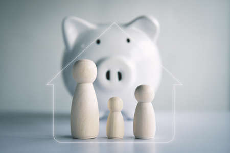 Wooden doll and white piggy bank to saving money for residence concept .budget, financial.の写真素材