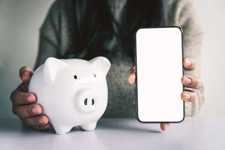 Woman hand and white piggy bank to saving money concept .budget, financial.の写真素材