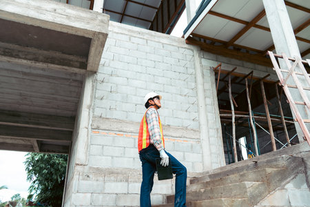 Construction worker holding digital tablet to inspects the building construction standards to ensure...