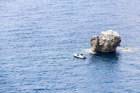 Islet by boat and divers in the sea in Sardinia, Italy  の写真素材