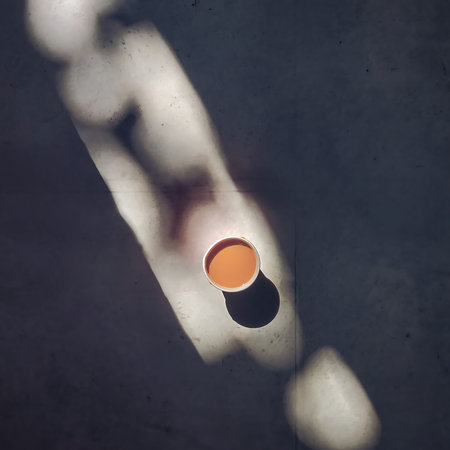 Orange cup of coffee on concrete floor with shadow. Minimal styleの写真素材