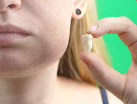 Blurry pose of a woman with toothache and a hand holding the extracted tooth, hocus on the handの写真素材