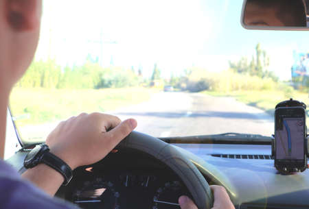 Man in the car and holding black mobile phone with map gps navigation, toned at sunset.の写真素材