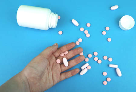 Pills and medicines in the hand on a blue backgroundの写真素材