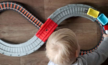 A little boy plays a children's railway. Mom is watching her son from above. The child is fascinated...