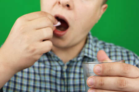 Serious man taking a pill standing at home
