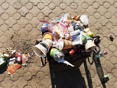Nikopol, Ukraine, May 20, 2019: a crowded trash can on the Ukrainian street, with garbage on paving slabs.のeditorial素材