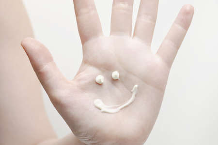 Sunscreen on the hand in the form of a sun and a smile. Hand cream, nourishing cream, personal care, moisturizerの写真素材