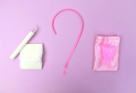 A woman holds a menstrual cup in her hand on a pink background. The concept of women's health,...