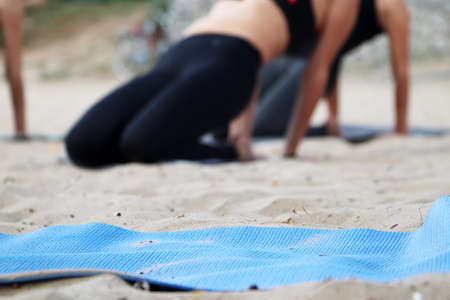 Yoga on the beach. Close-up of girls legs in lotus position. Blurred background for signature. Doing sports, Pilates, stretching outdoorsの写真素材