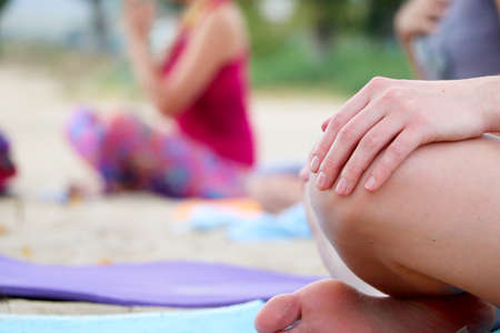 Yoga on the beach. Close-up of girls legs in lotus position. Blurred background for signature. Doing...