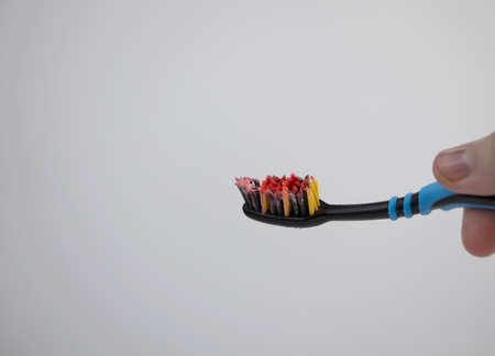 Toothbrush with blood closeup. A woman discovered bleeding gums while brushing her teeth. Gingivitis or periodontal diseaseの写真素材