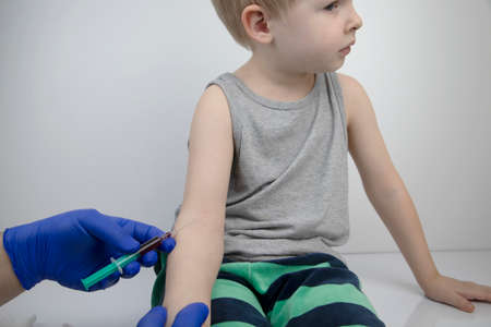 The doctor takes the boy blood from a vein. Taking blood from a child for research and laboratory...