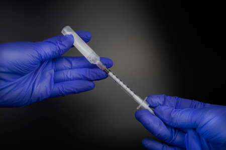 The doctor draws a medicine or substance for vaccination with an insulin syringe from a plastic...