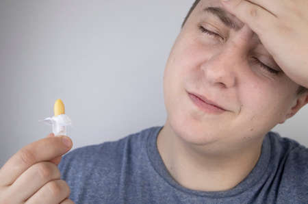 A man holds a rectal candle in his hand. A drug that is inserted into the rectum. Rectal suppository...