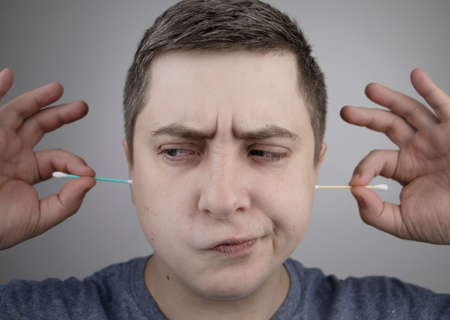 Plastic and bamboo chisels, toppers. A man chooses between a plastic and a wooden ear stick. The...