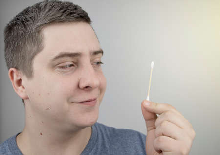 Plastic and bamboo chisels, toppers. A man chooses between a plastic and a wooden ear stick. The...