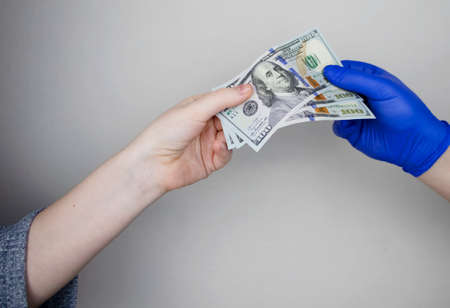 Patient's hand holds out money to the doctor. The concept of corruption in healthcare, bribery or...