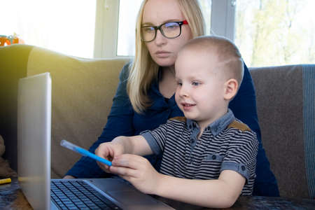Mom and son do their homework, study online on the Internet. The concept of preschool education,...