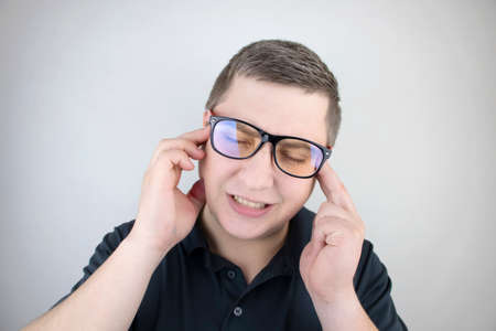 A man holds his head with his hands. Sensation of headache, migraine and dizziness. Headaches from stress or overworkの写真素材